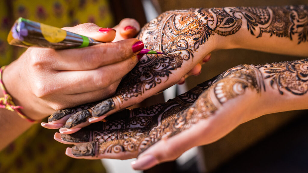 Close up of Mehndi being applied on Indian bride's hands