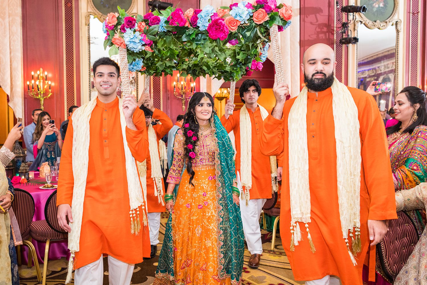 Mehndi bride dressed in orange lehenga choli making her entrance at Palmer House wedding. Photographed by Maha Studios