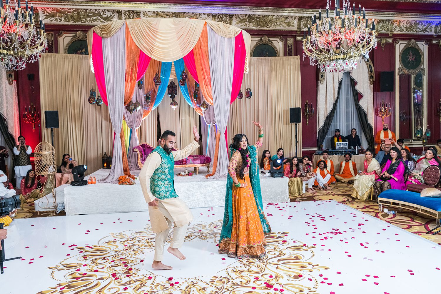 Pakistani bride and groom dance at their mehndi in the Red Lacquer Room at Palmer House. Photographed by Chicago wedding photogapher Maha Studios
