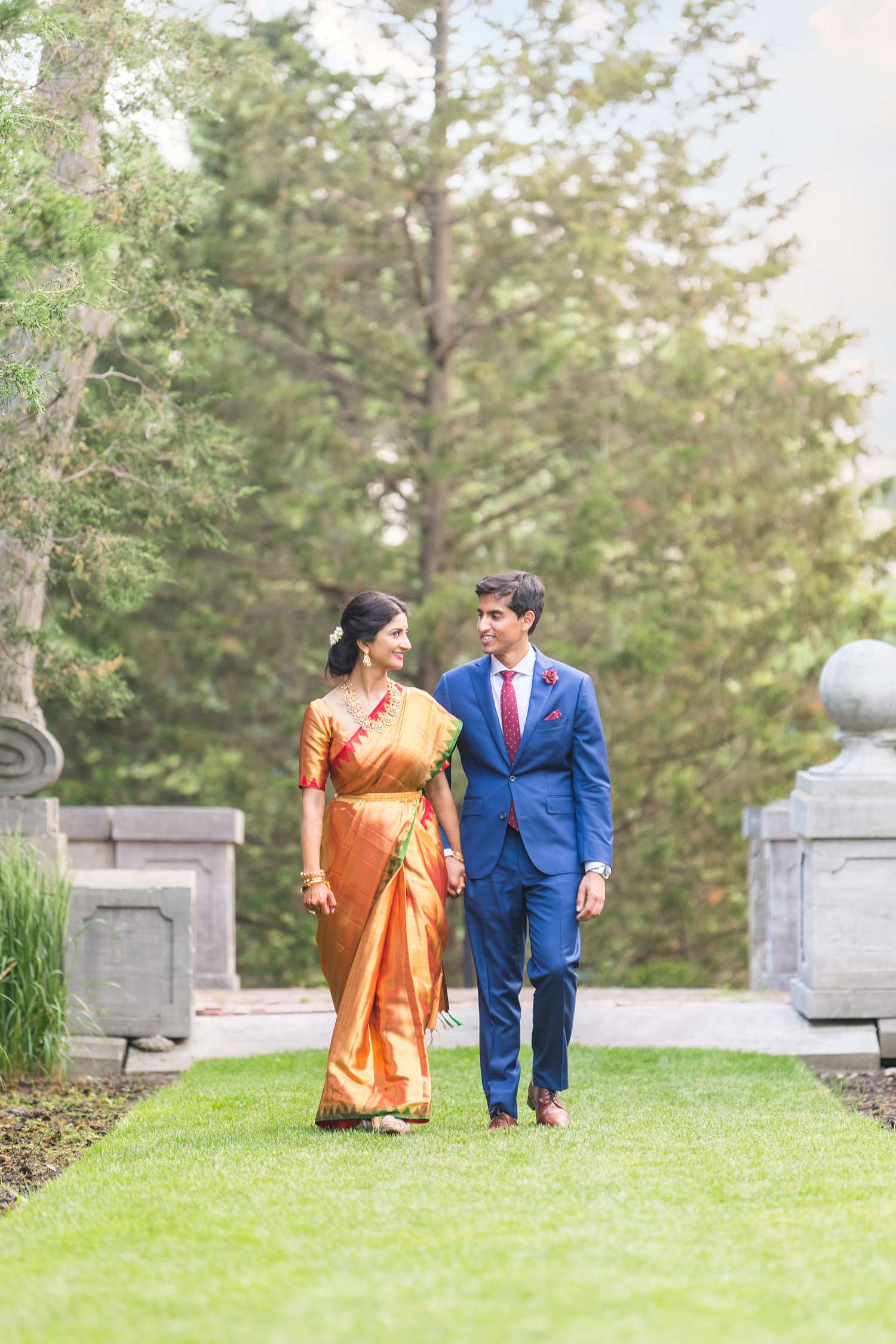 South Indian Bride orange wedding saree and groom wearing blue suit for wedding photos
